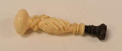 A EUROPEAN CARVED IVORY DESK SEAL in the form of a handshake with circling snake, 11cms long