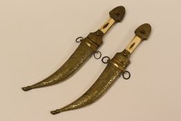 PAIR OF TURKISH DECORATIVE KNIVES with brass scabards, brass and bone handles and having curved