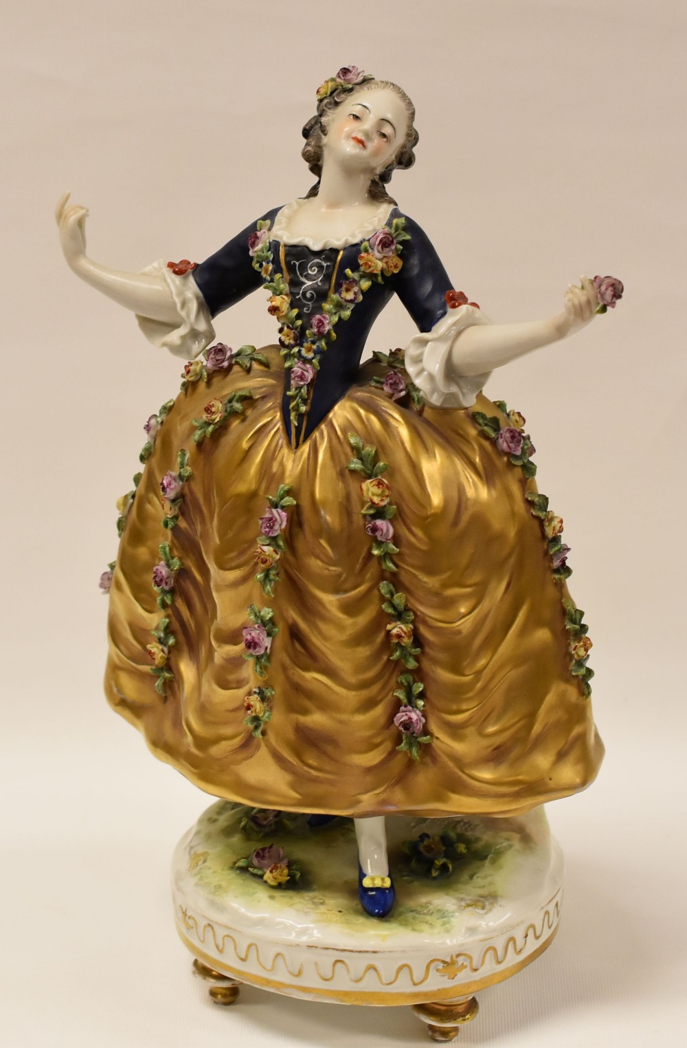 A GERMAN PORCELAIN FIGURE OF A LADY WITH FLORAL-ENCRUSTED DRESS on a raised circular base with