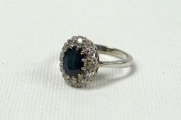 AN 18ct WHITE GOLD SAPPHIRE & DIAMOND CLUSTER RING, the centre oval sapphire surrounded by a