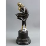 An Art Deco style bronze study of a young woman battling with a windy day on a stepped circular