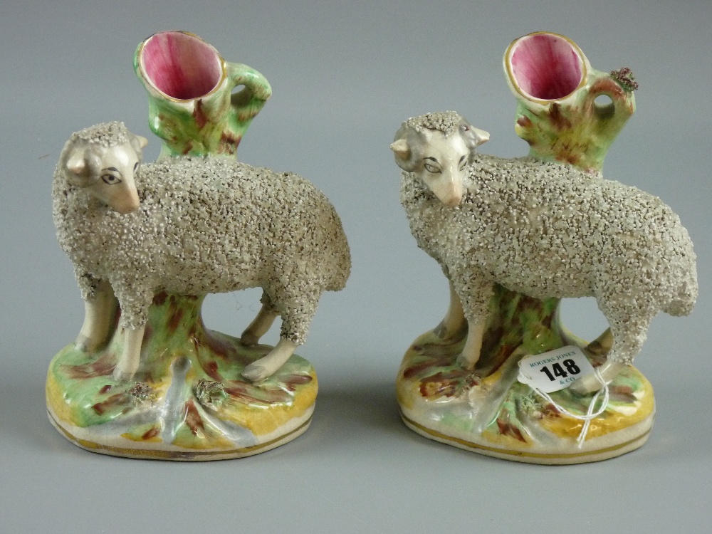 Two Victorian Staffordshire pottery spillholders modelled as rams standing on oval grassy banks with