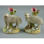 Two Victorian Staffordshire pottery spillholders modelled as rams standing on oval grassy banks with