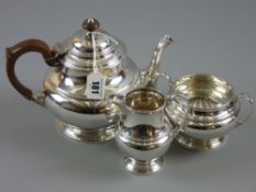 A three piece silver tea service with strap work bands on stepped pedestal bases, hallmarked