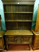 An antique style oak open base two door dresser with later plate rack, the doors with linenfold