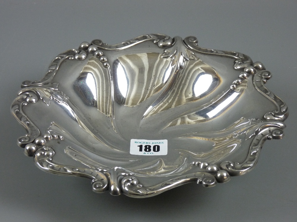 A hallmarked silver shaped dish with Rococo style edge decoration on four ball feet, Sheffield 1908,