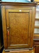 A Georgian oak single door hanging corner cupboard with brass knob and escutcheon with interior