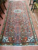 A red ground Persian Hamadan runner, 275 x 110 cms approximately