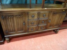 A reproduction oak Priory style sideboard with linenfold carved doors and three central drawers