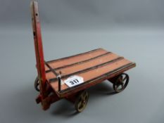 A vintage painted porter's trolley in red and pink livery with moving front axle and iron wheels, 23