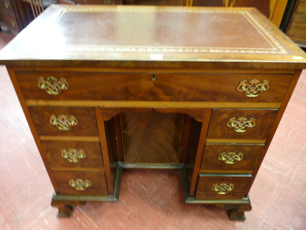 A neat early 20th Century walnut desk with gilt tooled red leather writing surface over a single