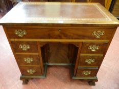 A neat early 20th Century walnut desk with gilt tooled red leather writing surface over a single