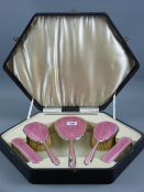 A hallmarked silver and pink enamel five piece dressing table set in a fitted case, Birmingham