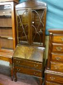 A 1930's walnut bureau bookcase with interior adjustable shelves behind twin shaped beaded doors and