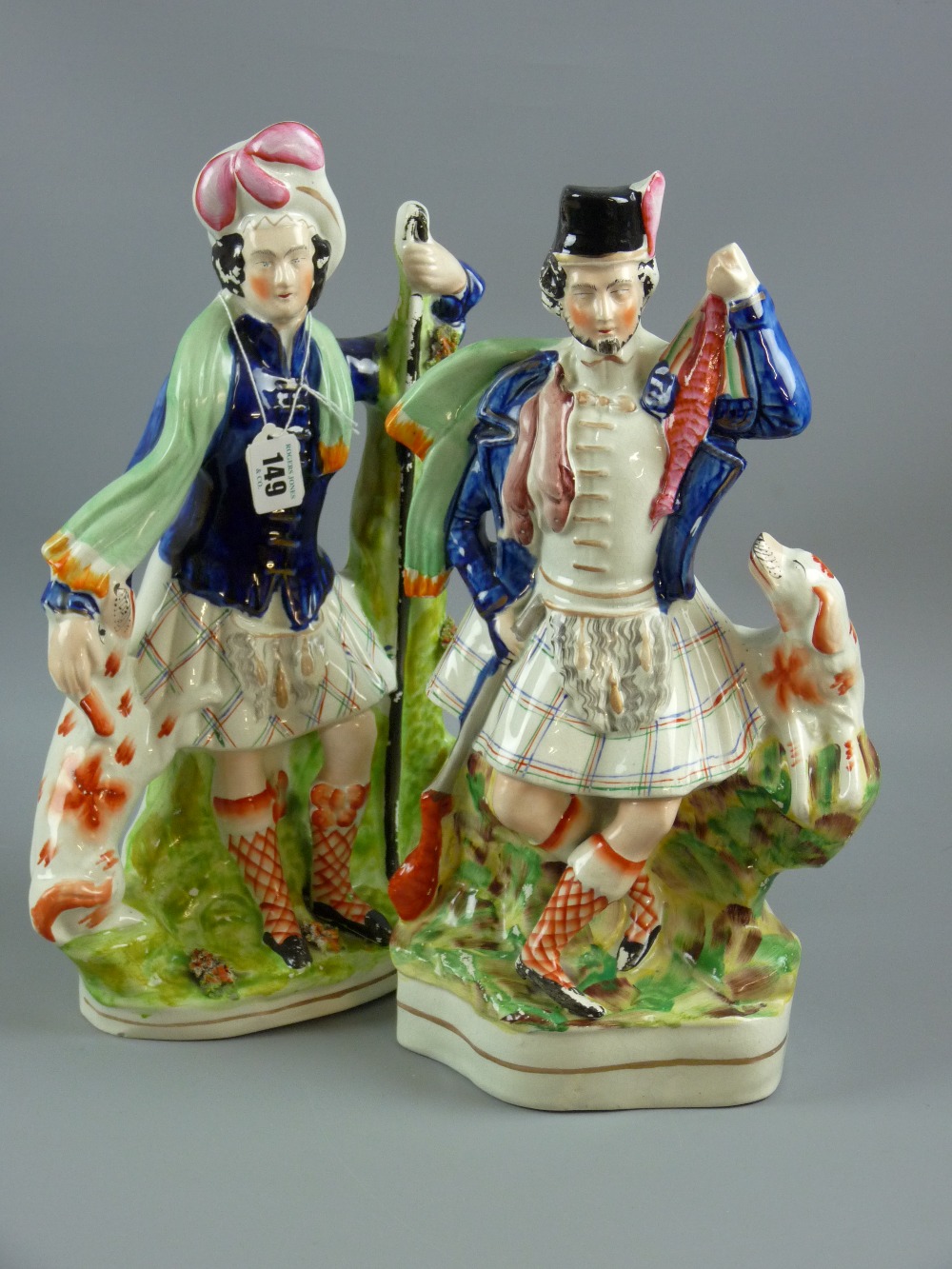 A pair of late 19th Century Staffordshire pottery flatback Scottish kilted figures with dogs, 38 cms