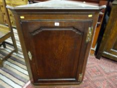 A 19th Century oak single door hanging corner cupboard with brass 'H' hinges and escutcheon,