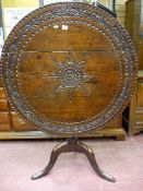 An 18th Century oak tilt top tripod table with later carving to the top, 75 cms high, 91 cms