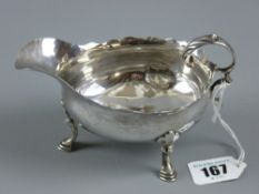 A Georgian silver sauce boat with scrolled handle on three shell and hoof supports, 4 ozs, London