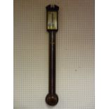 An antique mahogany stick barometer, pediment top with brass urn central finial, glazed opening door