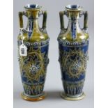 Doulton Lambeth stoneware - a near matching pair of twin handled vases of tapering form incised