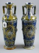 Doulton Lambeth stoneware - a near matching pair of twin handled vases of tapering form incised