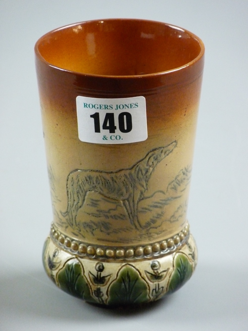 A Hannah B Barlow Doulton Lambeth stoneware beaker with leaf decorated bulbous base, sgraffito