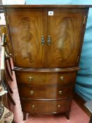 A reproduction mahogany bow front two door cupboard on chest, the three drawers with brass ring pull