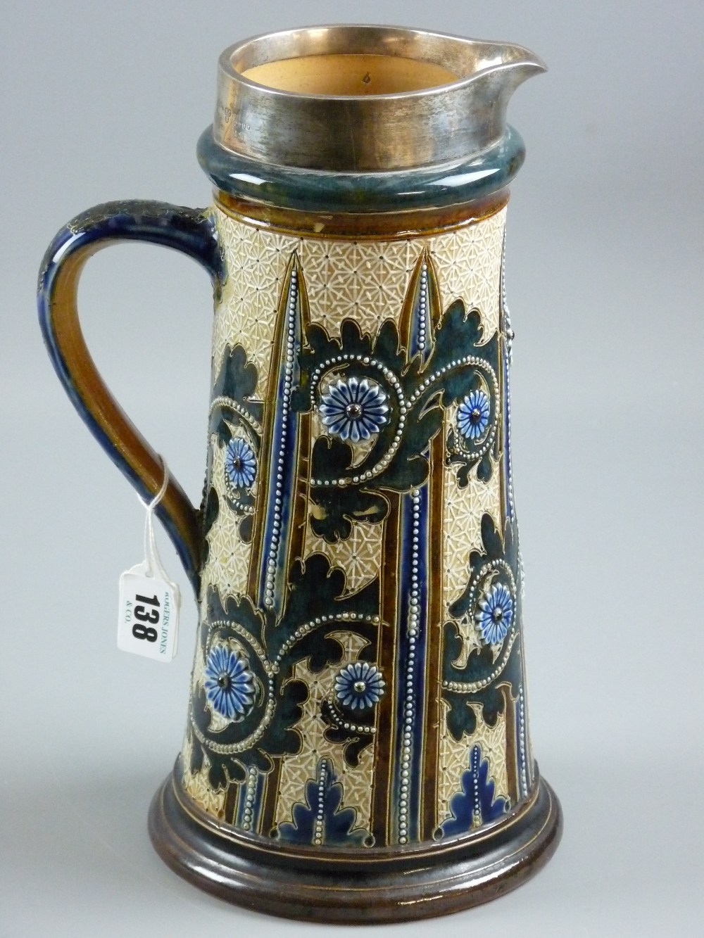 Doulton Lambeth - a silver collared stoneware jug by George Tinworth, 30 cms high, typically