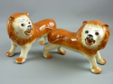 A pair of Staffordshire pottery standing lions with glass eyes, 25 x 35 cms