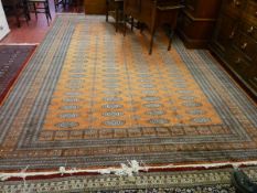 A LARGE PAKISTAN CARPET, rust ground multi bordered with tasselled ends and large block repeat