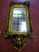 A REPRODUCTION GILT FRAMED WALL MIRROR with rectangular bevelled glass in a deep swept Rococo