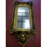 A REPRODUCTION GILT FRAMED WALL MIRROR with rectangular bevelled glass in a deep swept Rococo