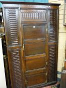 A LARGE TWO DOOR OAK CORNER CUPBOARD with carved reeded top and side decoration (fashioned from