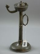 A PEWTER TALLOW LAMP, a circular based pewter tallow lamp with handle to the turned column, 26 cms