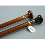 TWO WOODEN SHAFTED WALKING CANES, one with a silver ferrule and a black grip, the other with a white
