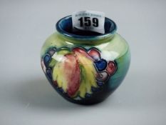 A MOORCROFT LEAF AND BERRY VASE, a 7 cms high vase decorated on a greeny blue ground, incised '