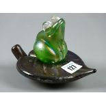 A KRIS HEATON ART GLASS FROG ASTRIDE A LEAF, iridescent green and glass sculpture, inscribed to