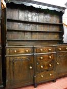 A GEORGE III CONWY VALLEY OAK BREAKFRONT DRESSER, a three shelf shaped belly rack with decorative