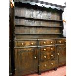 A GEORGE III CONWY VALLEY OAK BREAKFRONT DRESSER, a three shelf shaped belly rack with decorative