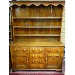 AN EARLY 19TH CENTURY ANGLESEY OAK DRESSER, the three shelf shape sided rack with decorative top