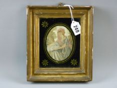 A SILK WORK PICTURE, an oval miniature silk work study of a seated lady with her pet with black gilt