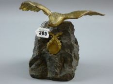 A GILT METAL FIGURE OF AN EAGLE with spread wings, mounted upon a rock with gilt metal swag