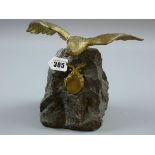 A GILT METAL FIGURE OF AN EAGLE with spread wings, mounted upon a rock with gilt metal swag