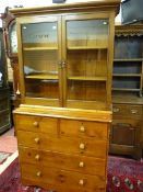 A VICTORIAN PINE BOOKCASE CHEST, a glazed two door top with interior shelves over a base of two