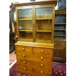 A VICTORIAN PINE BOOKCASE CHEST, a glazed two door top with interior shelves over a base of two