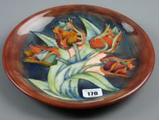 A MOORCROFT TULIP PLATE, a 26 cms diameter plate decorated on a tonal blue brown ground,