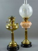 TWO VICTORIAN OIL LAMPS, brass with black pot bases, one with moulded pink glass font, etched