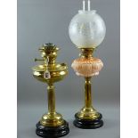 TWO VICTORIAN OIL LAMPS, brass with black pot bases, one with moulded pink glass font, etched