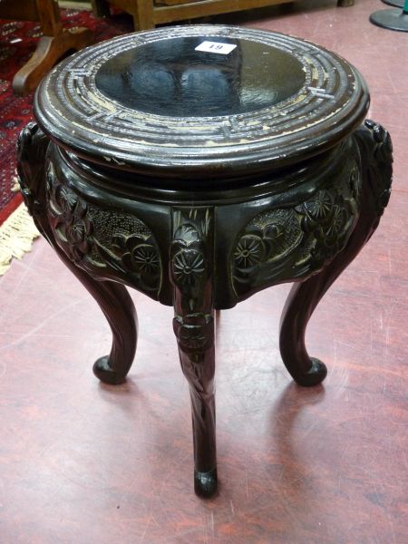 AN ORIENTAL CARVED WOOD STAND, a circular top with carved frieze and shaped legs, 45 cms high, 26