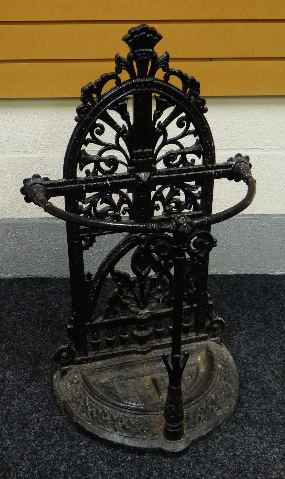 A CAST IRON UMBRELLA STAND of half-moon form with arched ornate back, 88cms high Provenance: The